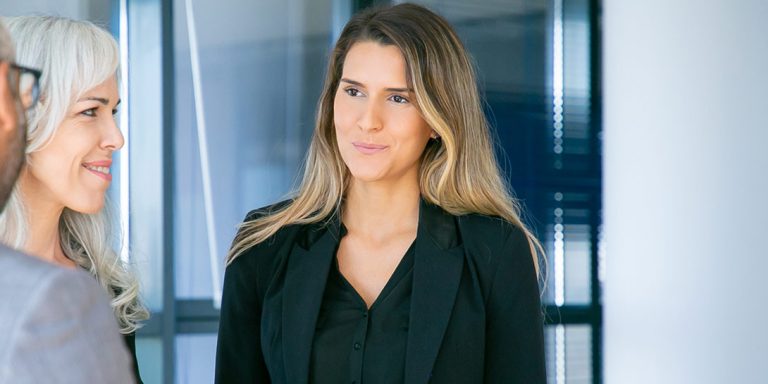 En kvinde står med en gruppe mennesker foran en glasvæg